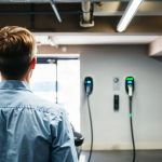 Salarié branchant sa voiture électrique sur une borne de recharge dans le parking de son entreprise