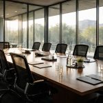 Deux dirigeants en costume signant un contrat dans une salle de réunion vitrée